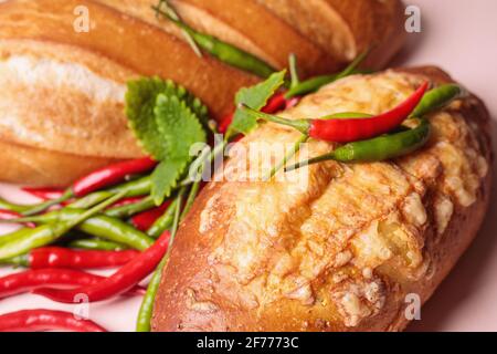 Frisches Brot auf dem Tisch mit roten und grünen Chilischoten. Nahaufnahme Stockfoto