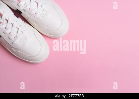 Flache Laie aus weißen Sport-Sneakers-Schuhen auf dem rosa Hintergrund. Fitness-Hintergrund. Gesundes Lifestyle-Konzept. Stockfoto