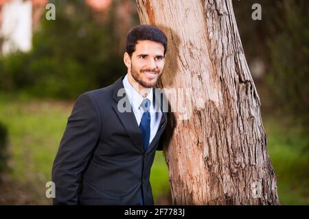 Ein Geschäftsmann umarmt einen Baumstamm Stockfoto