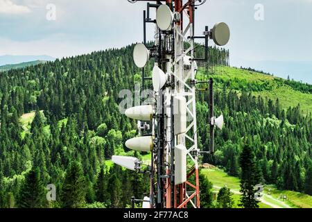 Telekommunikations-Sendeturm mit Antennen der Mobilfunkkommunikation in den Bergen Gegen Himmel und Wolken Stockfoto