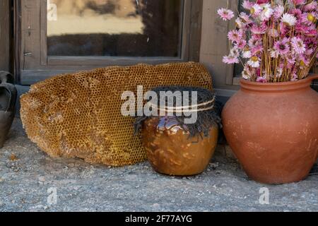 Honigtopf mit Blumen auf Holztisch mit Bienenplatte Hinter Stockfoto