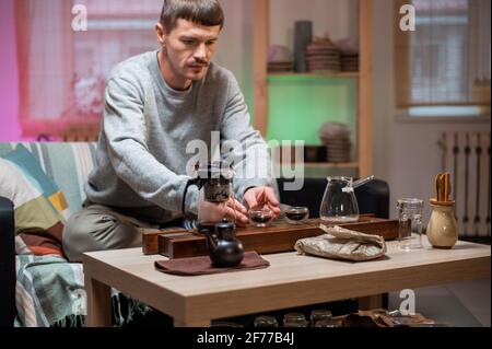 Brauen köstlichen starken chinesischen Tee. Bühne einer echten orientalischen Teezeremonie zu Hause mit einem speziellen Set von Bambus-Werkzeugen. Der Teemeister gießt heißes Wasser Stockfoto