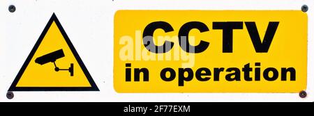 Nahaufnahme eines Warnzeichens, das anzeigt, dass das CCTV in Betrieb ist, schwarze Beschriftung auf einem gelben Sockel. Stockfoto