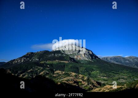 Vollmondnacht auf der Südwand von Pedraforca mit dem von einer Wolke bedeckten Pollegó-Gipfel (Berguedà, Katalonien, Spanien) Stockfoto