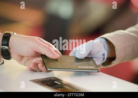Hand eines reifen Mannes, der seinen Pass nach der Registrierung zurücknimmt Vor dem Flug am Check-Schalter am modernen Flughafen Stockfoto
