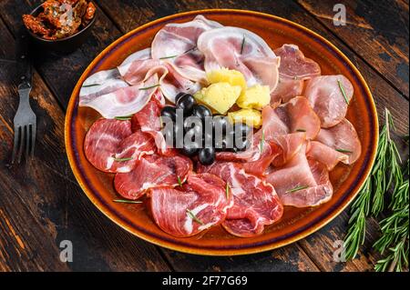 Italienische Fleischplatte mit Prosciutto-Schinken, bresaola, Pancetta, Salami und Parmesan. Dunkler Holzhintergrund. Draufsicht Stockfoto