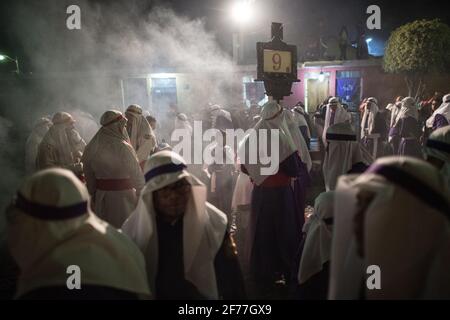Cucuruchos in lila Gewändern werden feierlich durch die Straßen von Antigua, Guatemala, während der traditionellen Feierlichkeiten der Weihnachtsfeier in der Karwoche Semana gefeiert. Stockfoto