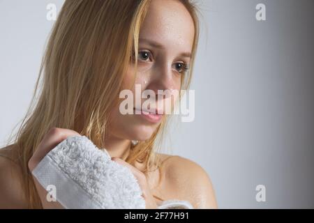 Junge schöne nasse Blonde kaukasische Frau wischt ihr Haar mit Weißes Handtuch Stockfoto