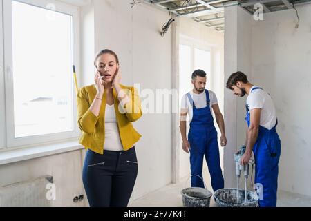 Frau, die auf einem Handy spricht. Zwei Reparaturwerkstätten in Uniform Stockfoto