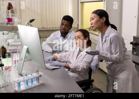 Gruppe von Wissenschaftlern, die am Tisch sitzen und Computer betrachten Überwachen und Arbeiten am Computer im Team im Labor Stockfoto