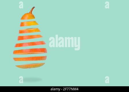Minimalidee mit schwebenden, reifen Birnen auf pastellgrünem Hintergrund. Vitamine, gesunde Ernährung Konzept. Birne in Scheiben, die in der Luft schwebt. Kreativ Stockfoto