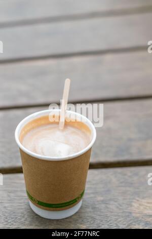 Recycelbare Kaffeetasse mit einem Stiring-Stick auf Holzoberfläche stehend, leckeres Koffein-Getränk in Papier Einweg-Tasse isoliert auf der Bank, neue eco Stockfoto