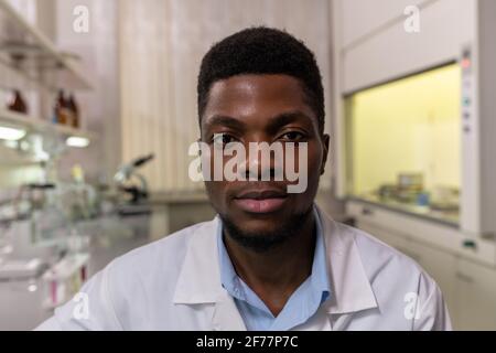 Porträt eines jungen afrikanischen Wissenschaftlers, der während der Arbeit die Kamera anschaut Im Labor Stockfoto