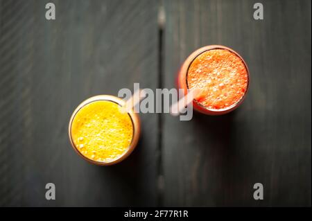 Draufsicht auf zwei Gläser Orangensaft mit Plastikstrohhalmen auf Holztisch. Saft Diät-Konzept Stockfoto