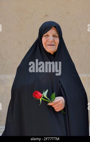 Iran, Yazd, von der UNESCO zum Weltkulturerbe erklärt, Alte Dame mit Rose Stockfoto