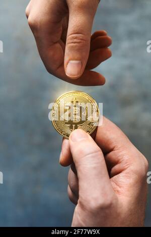 Zwei Hände tauschen eine goldene Bitcoin aus. Peer-to-Peer-Austauschkonzept. BTC und Kryptowährungen Geschäft auf einer digitalen dezentralen Finanzen Stockfoto