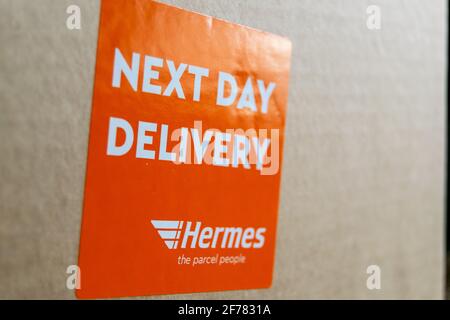 Thame, UK 25 Mar 2021: Orange Lieferung am nächsten Tag Hermes-Etikett auf dem Karton, Logo-Aufkleber auf einem Paket, schneller Kurierdienst geliefert, groß Stockfoto