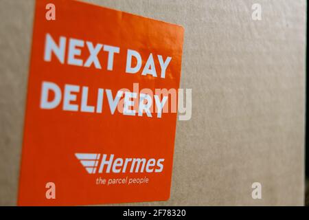 Thame, UK 25 Mar 2021: Orange Lieferung am nächsten Tag Hermes-Etikett auf dem Karton, Logo-Aufkleber auf einem Paket, schneller Kurierdienst geliefert, groß Stockfoto