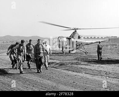 Evakuierung Des Koreanischen Kriegsverfalles. Die Korpsmänner der Marine Herald B. Williams, James E. Carr und William N. Shipworth tragen einen verwundeten Mann aus einem Evakuierungshubschrauber des US Marine Corps HO3S-1 in ein Krankenhaus in Korea. Der Hubschrauber stammt von der Staffel VMO-6. Das Originalfoto datiert vom 3. Oktober 1950, in diesem Fall wurde es wahrscheinlich während der Operationen des Marine Corps in der Nähe von Seoul, Korea, aufgenommen. Stockfoto