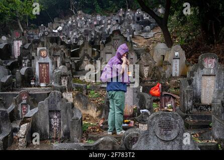 Während des Ching Ming Festivals in Hongkong betet eine Frau vor der Grabkammer ihrer Familie auf einem Friedhof.das jährliche Ching Ming Festival, Wenn Menschen die Gräber von verstorbenen Verwandten besuchen und Opfergaben in Erinnerung und Respekt hinterlassen, während die Regierung Hongkongs versucht, die Anzahl der COVID-19-Coronavirus-infizierten Fälle unter Kontrolle zu halten, während mehr Menschen geimpft werden. Stockfoto