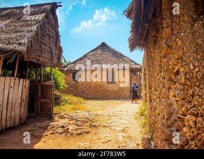 Wasini Island, Kenia, AFRIKA - 26. Februar 2020: Frau und typische Steinhäuser in einem afrikanischen Dorf auf der Insel Wasini. Es ist ein kleines Dorf in Stockfoto