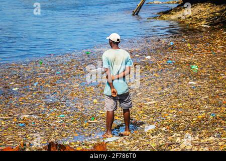Auf der Insel Wasini in Kenia steht ein Mann im Müll auf See. Es handelt sich um Kunststoffe im Indischen Ozean, Afrika. Das Bordell verdirbt den Blick auf die Stockfoto