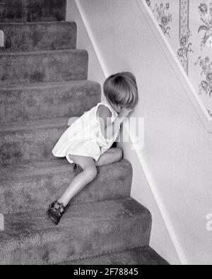 EIN UNGLÜCKLICHES KLEINES MÄDCHEN AUS DEN 1970ER JAHREN, DAS WEINEND DIE AUGEN REIBT UND AUF EINEM TEPPICH SITZT STAIRS - J13170 HAR001 HARS HIDING MOODY HEALTHINESS HOME LIFE COPY SPACE RISIKO SPIRITUALITÄT IN VOLLER LÄNGE HANDELN BEUNRUHIGT SCHWARZWEISS BESORGT TRAURIGKEIT REIBEN STRAFE WELLNESS-STRATEGIE KRAFTVOLLEN STOLZ GEFÜHL STIMMUNG KONZEPTUELLE GLUM VERHALTEN EMOTION EMOTIONALE EMOTIONEN WACHSTUM JUGENDLICHE FEHLVERHALTEN ELEND FALSCH SCHWARZ UND WEISSE KAUKASISCHE ETHNIZITÄT HAR001 ALTMODISCH Stockfoto