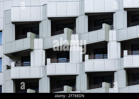 Belüftete graue Fassade. Abstrakter architektonischer Hintergrund. Quadratisches geometrisches Muster aus Fliesen auf den Balkonen eines Büro- oder Wohngebäudes. Co Stockfoto