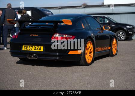 Ein Porsche GT3 RS Supersportwagen in Schwarz mit orangefarbener Verkleidung bei einem Track Day Meeting. Stockfoto