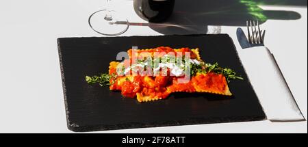 Vier mit Käse gefüllte Ravioli in Tomaten- und Basilikumsoße auf dem schwarzen Steinteller, einem berühmten Gericht aus der französischen Stadt Nizza Stockfoto