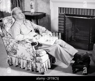 MANN AUS DEN 1950ER JAHREN, DER SICH IN EINEM MIT CHINTZ BEDECKTEN SESSEL RUHTE UND DACHTE IM WOHNZIMMER MIT ZEITUNG IN SEINEM SCHOSS GEFALTET - S1073 HAR001 HARS REFLECTIVE THINK EASY CHAIR IN REFLECTING PONDER ERWÄGEN IN GEDANKEN VERLOREN EINFACHE FUSSHOCKER POLSTERUNG CHINTZ NACHDENKLICH MEDITIEREN MEDITATIVE MITTE-ERWACHSENE MITTE-ERWACHSENE MANN ENTSPANNUNG RUHE SCHWARZ UND WEISS KAUKASISCHE ETHNIE, WENN MAN BEDENKT, DASS HAR001 ALTMODISCH IST Stockfoto