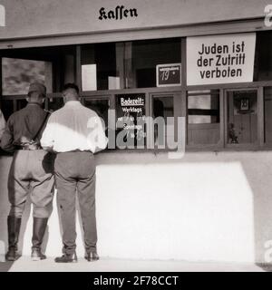 1930ER-JAHRE ZWEI MÄNNER EINER IM NAZI-HUTHEMD JACK STIEFEL IM CAFÉ-SCHILD IM FENSTER SAGT EINGESTÄNDNIS VON JUDEN IST VERBOTEN DEUTSCHLAND - S5962 HAR001 HARS FULL-LENGTH DEUTSCHLAND PERSONEN MÄNNER RISKIEREN B&W TRAURIGKEIT IST KATASTROPHE RELIGIÖSES ÄUSSERES VERBOTEN SIND IN DER AUFNAHMEPOLITIK KONZEPTUELLE NAZI-FASCHISTISCHE VERFOLGUNG EINGESTÄNDLICHKEIT FASCHISMUS SAGT ANTISEMITISMUS SCHWARZ-WEISS KAUKASISCHEN ETHNIZITÄT HAR001 ALTMODISCH EINGESCHRÄNKT Stockfoto