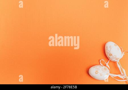 Weiße Ostereier auf orangefarbenem Hintergrund. Konzept der Frühlingsferien Stockfoto