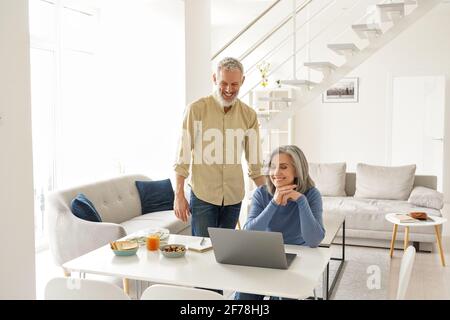 Glückliches reifes Seniorenpaar, das sich zu Hause auf einem Laptop virtuell trifft. Stockfoto