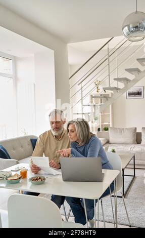 Ältere Paare, die zu Hause Bankdokumente mit einem Laptop überprüfen. Stockfoto