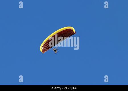 Paramotor im Flug gegen den blauen Himmel. Ein Gleitschirm mit Motor Stockfoto