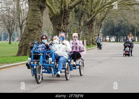 Ältere Frauen tragen Gesichtsmasken und reiten auf einem Vierrad in einem Park während der Coronavirus-Epidemie in London, England, Großbritannien Stockfoto