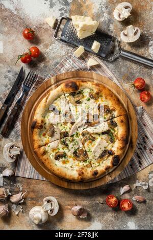 Italienische Pizza mit Huhn und Pilzen auf einem Holzbrett. Stockfoto