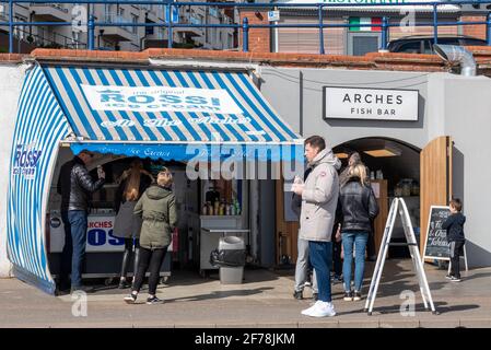 Menschen am Rossi-Eisstand und an der Arches-Fischbar in Southend on Sea, Essex, Großbritannien. Kunden für Takeaway-Bars während der COVID 19-Sperre Stockfoto