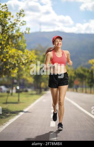 In voller Länge Porträt einer jungen Frau beim Joggen in der Stadt an einem Sommertag Stockfoto