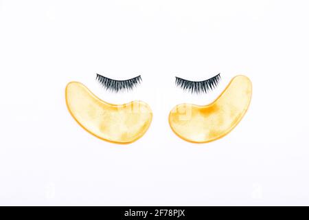 Falsche Wimpern und goldene Flecken auf weißem Hintergrund. Der Blick von oben. Stockfoto