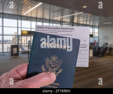 Nachbau des Flughafenterminals mit der Hand eines Geschäftsmannes, der den USA-Pass hält Und Impfpass für Coronavirus Stockfoto