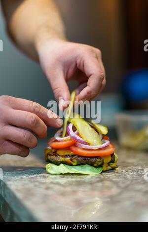 Nahaufnahme der Hände eines unbekannten kaukasischen Küchenchefs burger auf der Theke in der Küche im Restaurant oder Zu Hause Stockfoto