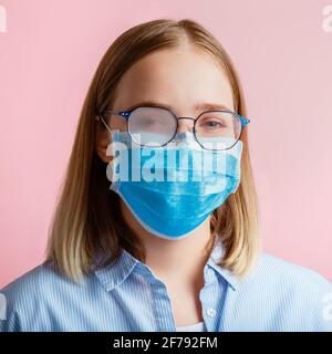 Neblige Brille trägt auf Frau. Frau in medizinischen Schutz Gesichtsmaske und Brillen wischt verschwommen neblig vernebelte Gläser auf rosa Hintergrund. Covi Stockfoto