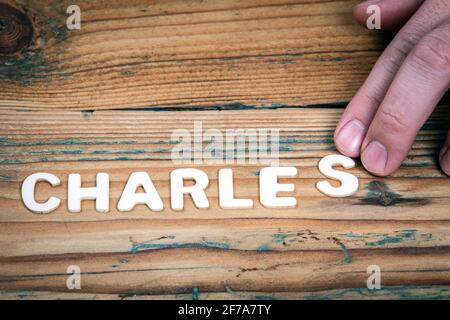 CHARLES. Name der Männer und Jungen. Geburtstagskonzept. Weiße Buchstaben des Alphabets auf einem hölzernen Hintergrund. Stockfoto