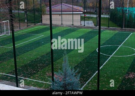 Eingezäunter Sportplatz mit Kunstrasen. Abends. Stockfoto