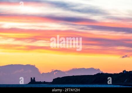 Wolkiger, dramatischer Morgenhimmel über dem Meer und der Küste von Kent in Reculver mit den Wahrzeichen-Zwillingstürmen der ruinierten Kirche aus dem 12. Jahrhundert auf der kleinen Landzunge, die an der Sächsischen Küste liegt. Wolkenschichten über dem Meer, die verschiedene Farbgrade reflektieren. Stockfoto