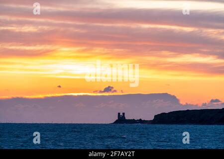 Wolkiger, dramatischer Morgenhimmel über dem Meer und der Küste von Kent in Reculver mit den Wahrzeichen-Zwillingstürmen der ruinierten Kirche aus dem 12. Jahrhundert auf der kleinen Landzunge, die an der Sächsischen Küste liegt. Wolkenschichten über dem Meer, die verschiedene Farbgrade reflektieren. Stockfoto