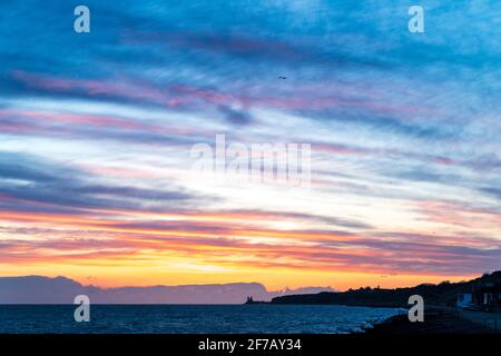 Wolkiger, dramatischer Morgenhimmel über dem Meer und der Küste von Kent in Reculver mit den Wahrzeichen-Zwillingstürmen der ruinierten Kirche aus dem 12. Jahrhundert auf der kleinen Landzunge, die an der Sächsischen Küste liegt. Wolkenschichten über dem Meer, die verschiedene Farbgrade reflektieren. Stockfoto