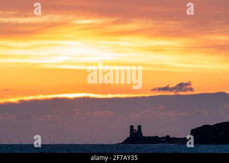 Wolkiger, dramatischer Morgenhimmel über dem Meer und der Küste von Kent in Reculver mit den Wahrzeichen-Zwillingstürmen der ruinierten Kirche aus dem 12. Jahrhundert auf der kleinen Landzunge, die an der Sächsischen Küste liegt. Wolkenschichten über dem Meer, die verschiedene Farbgrade reflektieren. Stockfoto